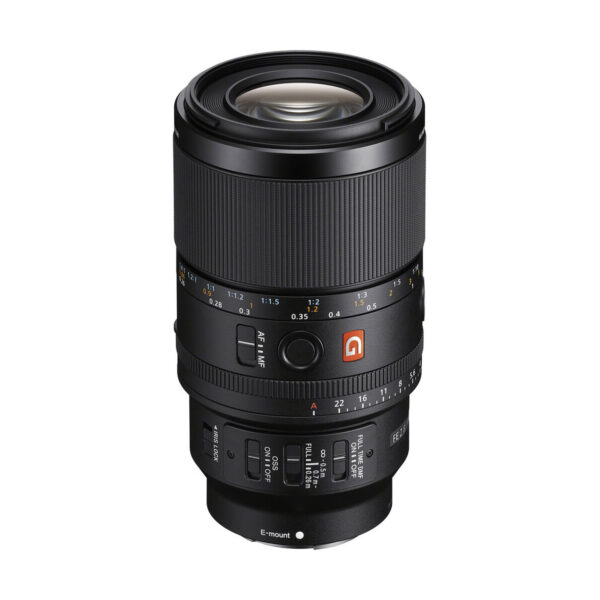 Musta Sony FE 90mm f/2.8 G OSS -kameran objektiivi, jossa on useita säätörenkaita, kytkimiä ja yksityiskohtaisia merkintöjä, on esillä pystyasennossa valkoisella pohjalla.