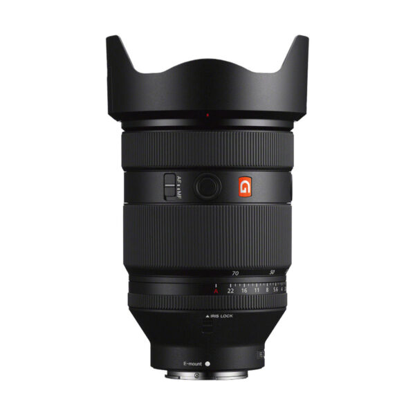 Musta Sony FE 28-70mm f2 GM -objektiivi, jossa on vastavalosuoja, säätörenkaat, kytkimet ja E-mount-kiinnitys, seisoo pystyssä valkoista taustaa vasten.