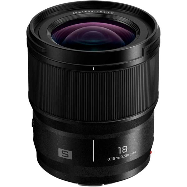 Panasonic Lumix S 18mm f/1.8 -kameran musta objektiivi seisoo pystyasennossa valkoisella pohjalla korostaen sen etulasia ja uurrettua tarkennusrengasta.