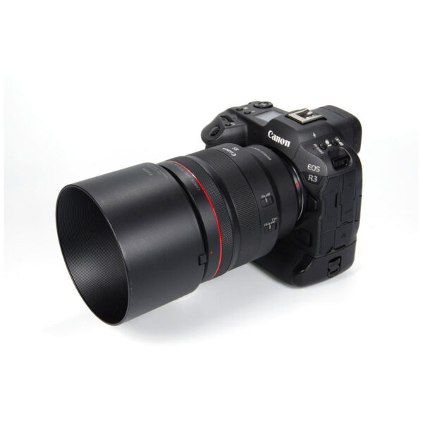 Musta Canon EOS R3 -digitaalikamera, johon on kiinnitetty Canon RF 85mm f/1.2 L USM -objektiivi, kuvakulmassa valkoisella taustalla.