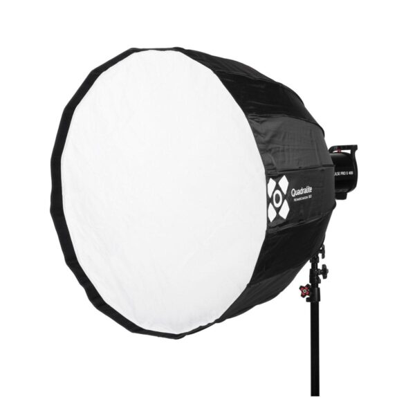 Quadralite Deep Hexadecagon 90cm Softbox - Bowens, jossa on musta ulkopinta ja valkoinen etuosa, on asennettu studiovalotelineeseen ja kulma on hieman vasemmalle. Quadralite-brändi on näkyvissä sivussa.