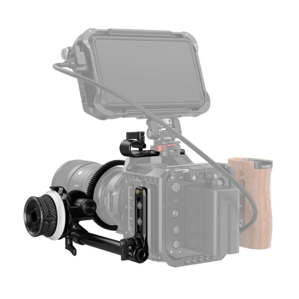 Lähikuva ammattikäyttöön tarkoitetusta kameralaitteesta, jossa on SmallRig 3010 Mini Follow Focus, suuri objektiivi, ulkoinen näyttö ja puinen kahva. Suurin osa harmaasta kamerarungosta erottuu mustasta kiinnitetystä varustuksesta.