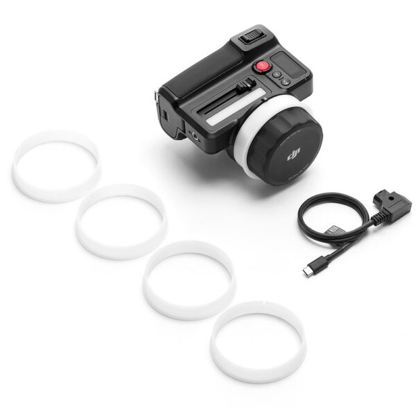 DJI Focus Pro Hand Unit, musta elektroninen kameran lisävaruste, jossa on suuri säätöpyörä, neljä valkoista muovirengasta ja musta USB-C-kaapeli sovittimella, näkyy valkoisella pohjalla.