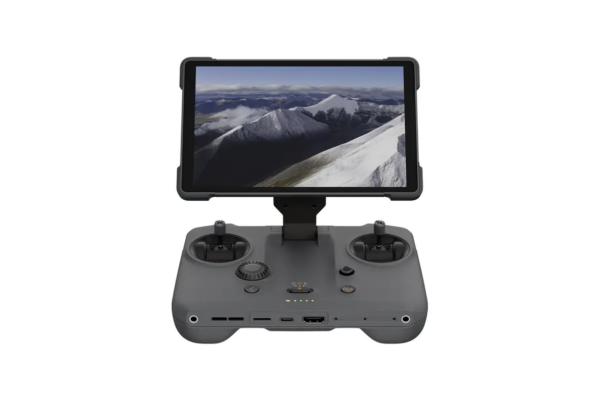 DJI RC Pro 2 -ohjain on harmaa lennokin kauko-ohjain, jossa on kaksi joystickiä, useita painikkeita ja asennettu näyttö, jossa näkyy ilmakuva lumisista vuorenhuipuista pilvisen taivaan alla.